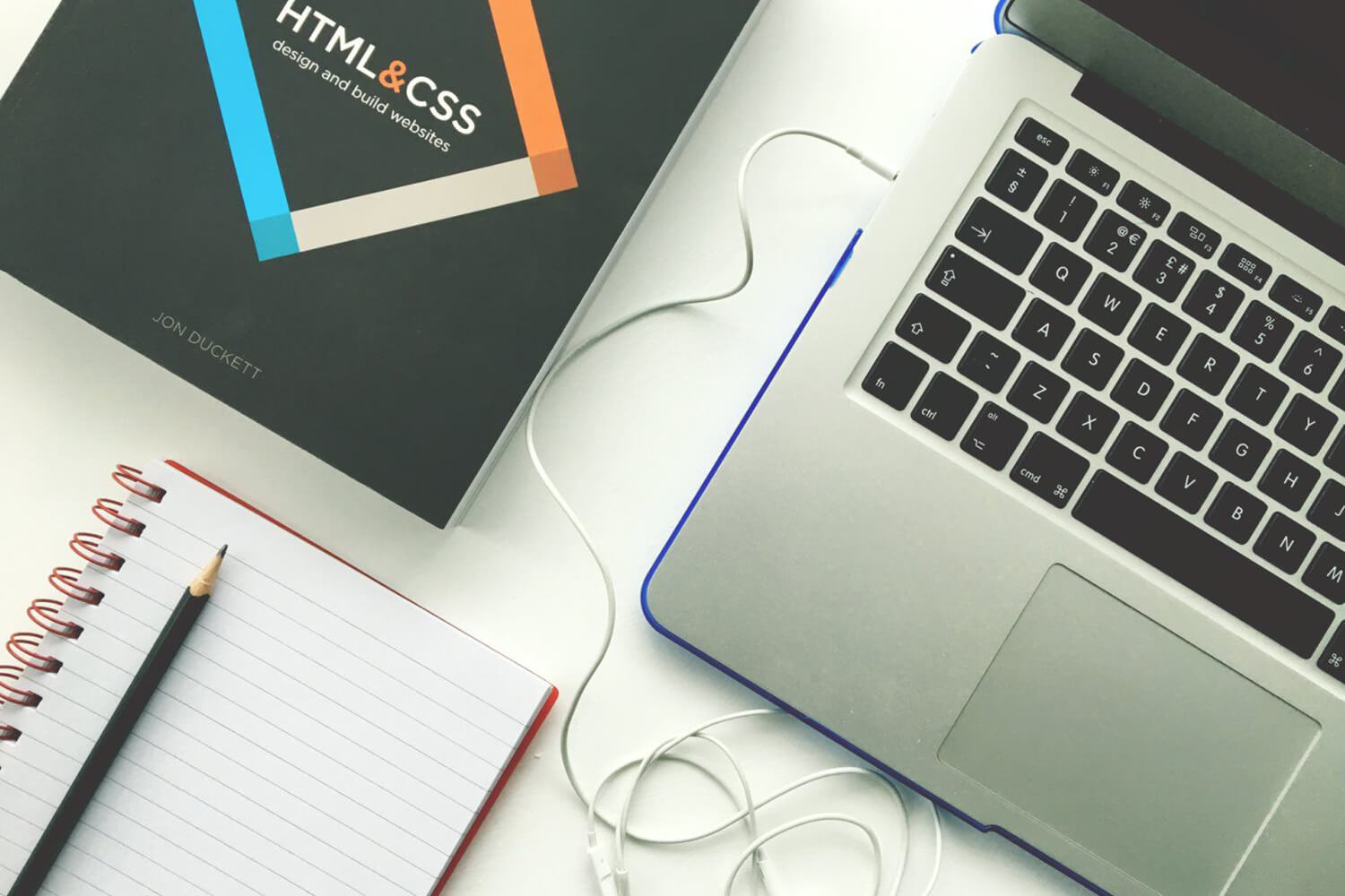 laptop, notebook, and HTML book on a table